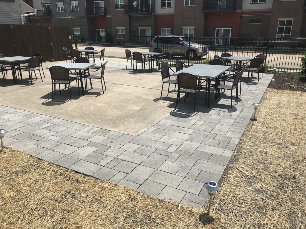 Outdoor patio with tables and chairs at apartment complex.